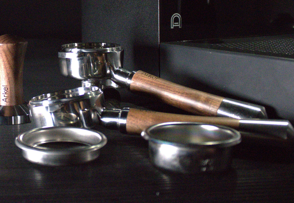 arkel bottomless portafilters next to tamper and baskets