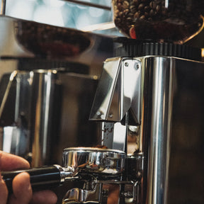 ECM C-Manuale 54 Silver Grinder grinding coffee beans into a portafilter basket