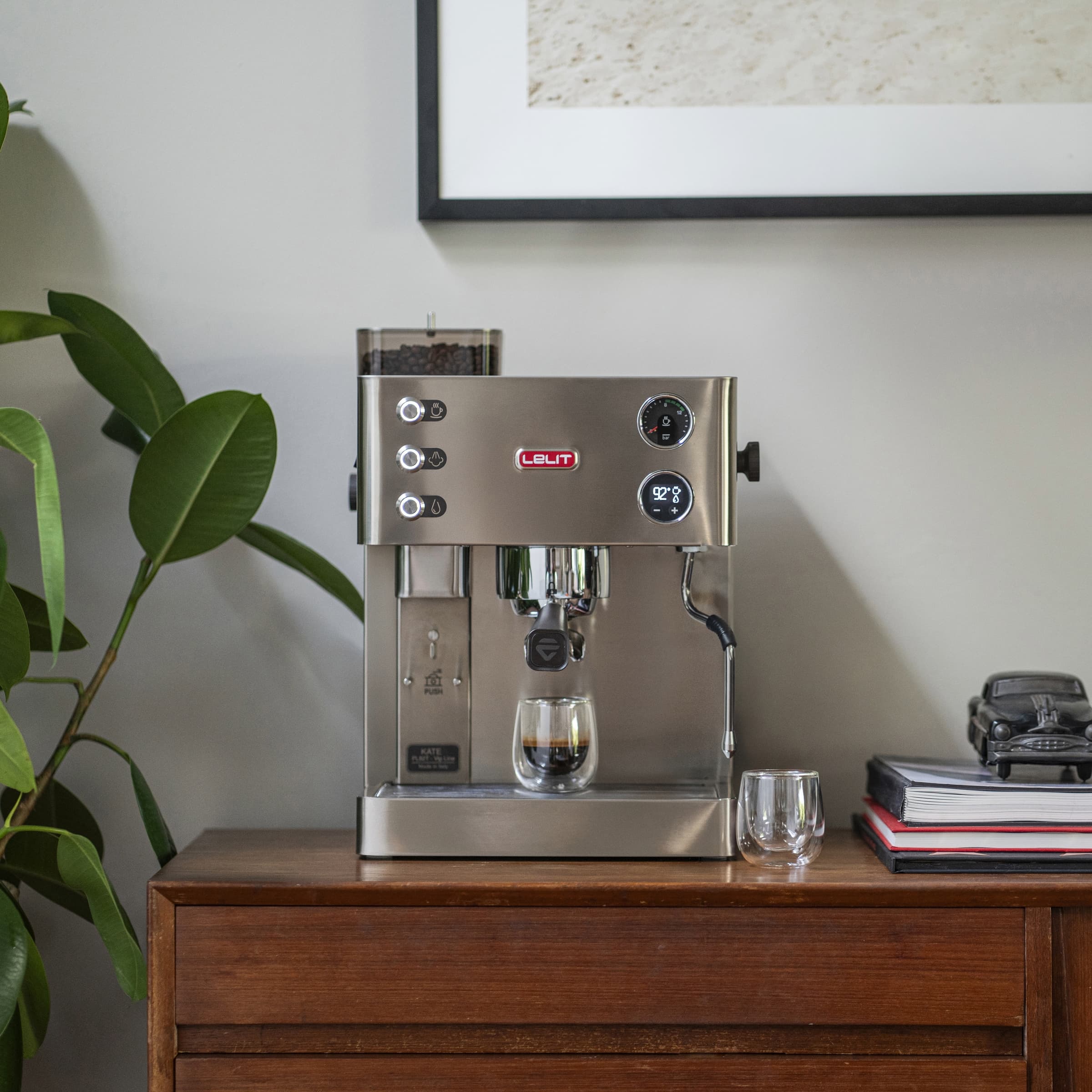 Lelit kate coffee machine with grinder built in on wooden cupboard pouring a shot