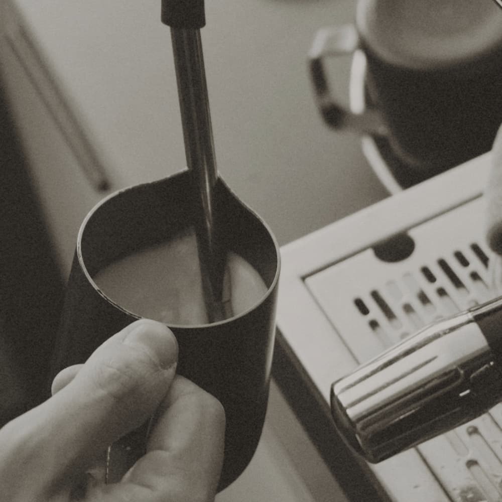 barista steaming milk in pitcher