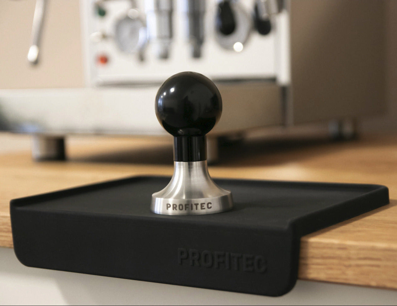 Black Profitec tamping mat on wooden countertop with profitec tamper