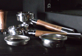 arkel bottomless portafilters next to tamper and baskets